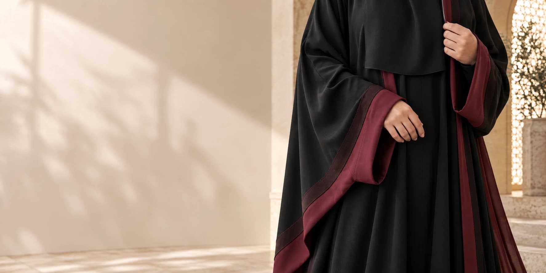 Close-up of black niqab fabric and burgundy-trimmed abaya sleeves